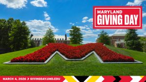 A scenic view of the University of Maryland campus featuring the iconic "M" garden made of red flowers on a grassy hill. The image includes a "Maryland Giving Day" logo in the top right corner and a red banner at the bottom announcing the event date as March 4, 2026, with the URL givingday.umd.edu.