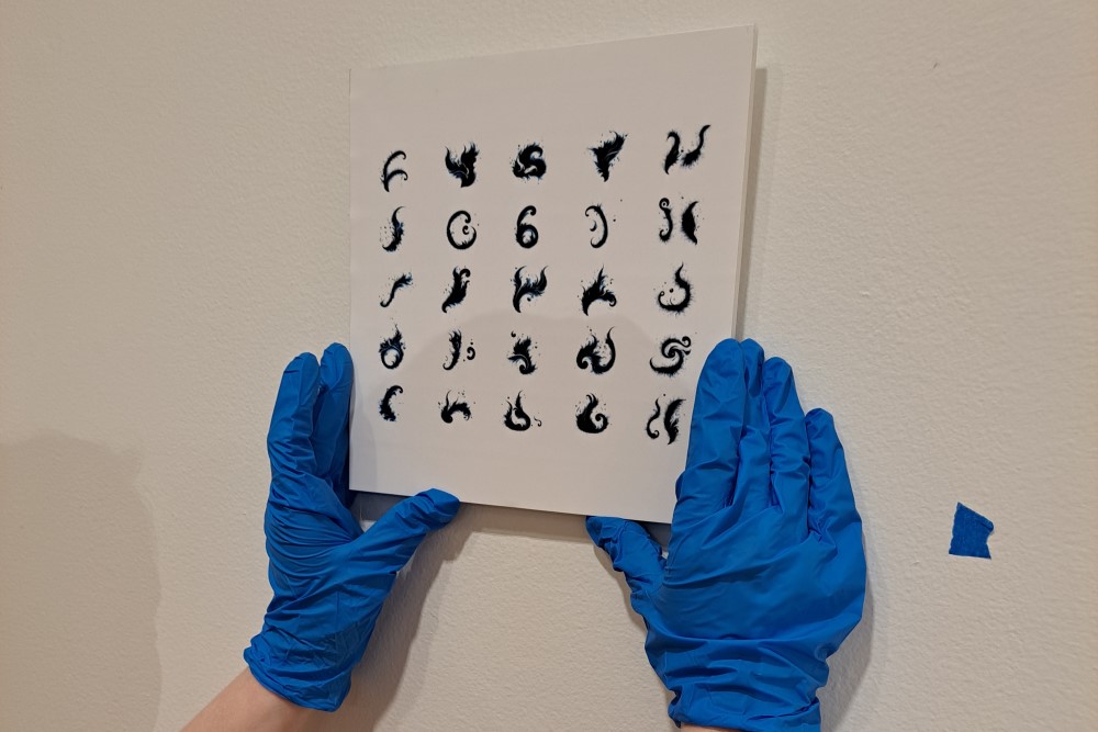 Hands mounting a piece of art on a wall for an exhibit