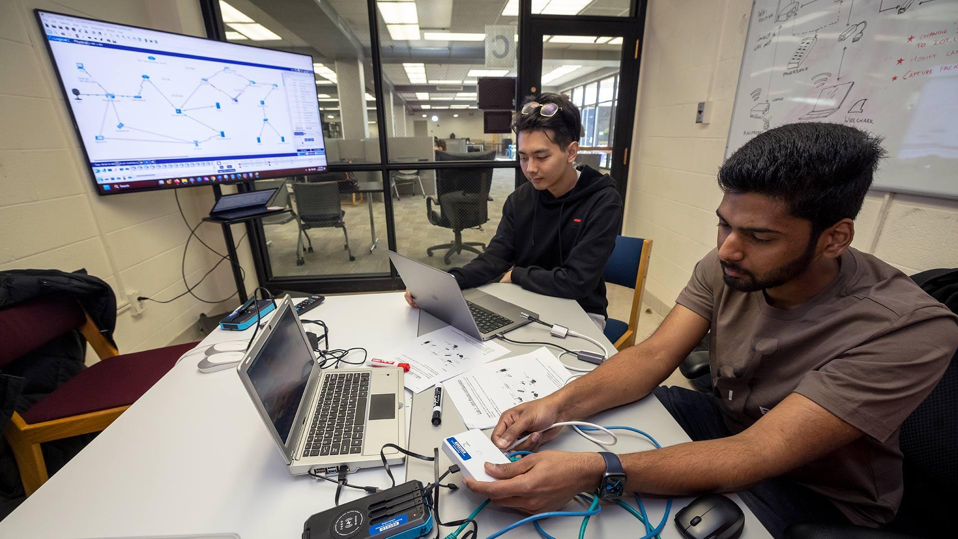 Tianming Zhou '23 , center, and Abhijith Anugu M.I.M. '23 work through a basic network connection in one of the iSchool labs. (Photo by Stephanie S. Cordle)