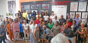 Residents and supporters gathering at the unveiling of the Southside mural at Grind AVL. Students analyze archival records on the urban renewal history it depicts.