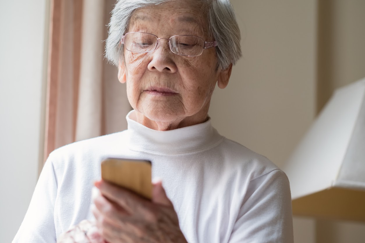 older woman looking down at a phone older woman looking down at a phone